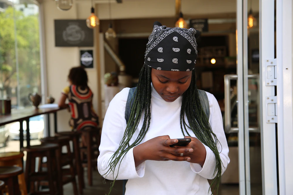 Woman in a casual white top using her phone outside a café